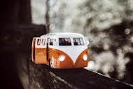 Close-up of a vintage toy campervan on a wooden beam with a bokeh background.